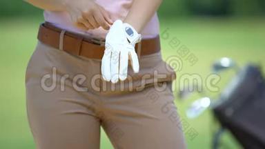女子在比赛前戴白色高尔夫球手套，<strong>运动器材</strong>和训练，爱好